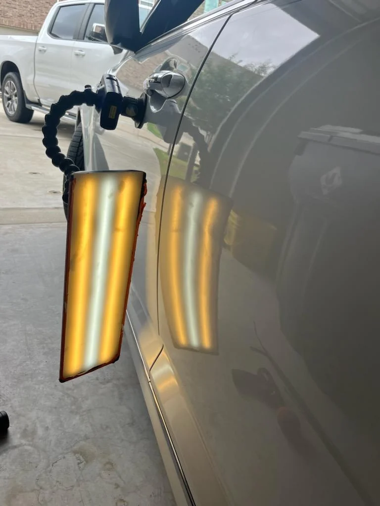Side-panel ding being pulled with PDR rods — factory paint preserved